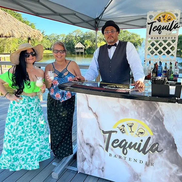 Invitadas posando con el bartender junto a la barra de mármol